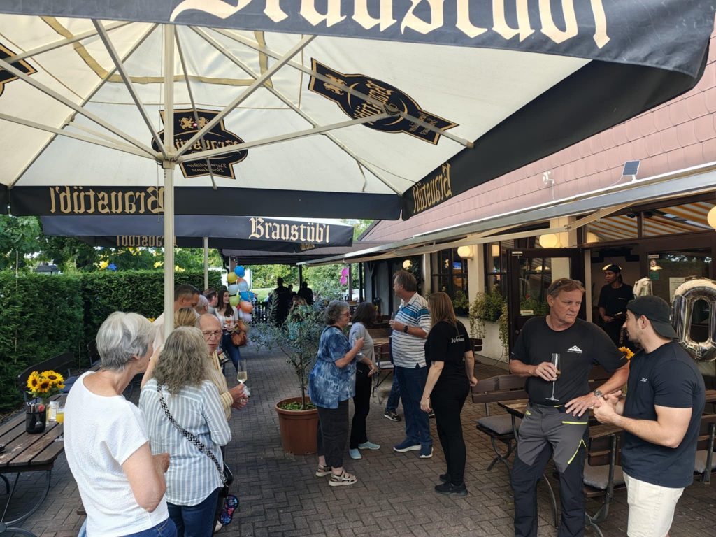 Gäste stoßen im Biergarten der Gaststätte Weiherhaus auf das Jubiläum an.