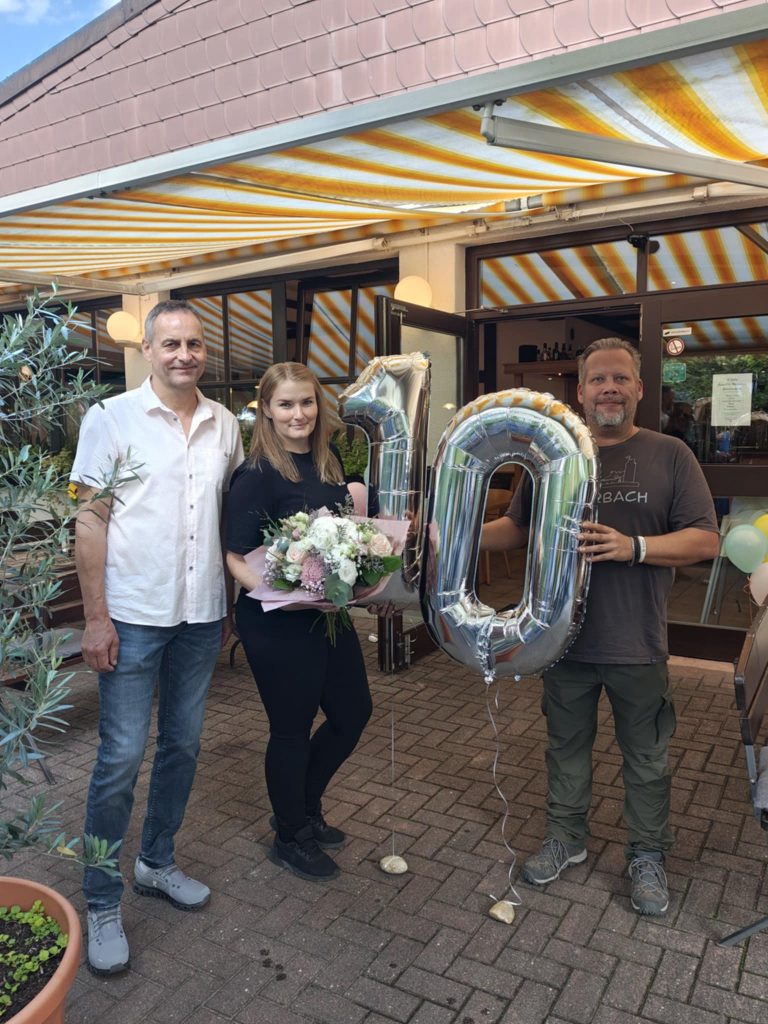 Eugenia steht mit Vereinsvertretern zusammen und nimmt Glückwünsche entgegen.